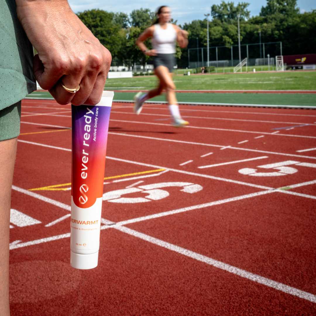 Warmte creme op een atletiekbaan met een hardlopend persoon.