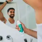 Man spuit deodorant van Ever Ready onder zijn oksels in de badkamer