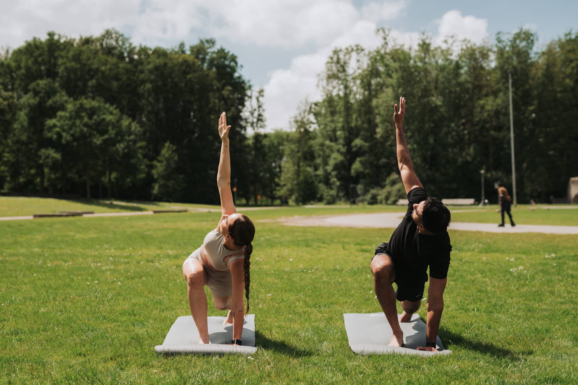 Doen van rekken en strekken oefeningen in het park op een matje tijdens mooi zomers weer om fit en gezond te blijven