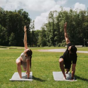 Yoga op een matje in het park. man en vrouw sporten samen tijdens mooi zomers weer.